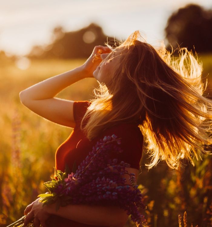 Woman in red dress whirls in the rays of evening sun